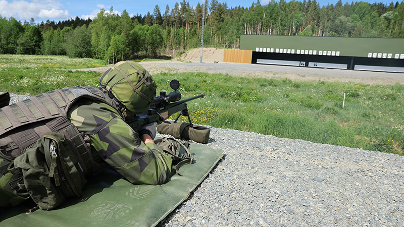 Soldat ligger ner och siktar med automatgevär mot en skjutbana.