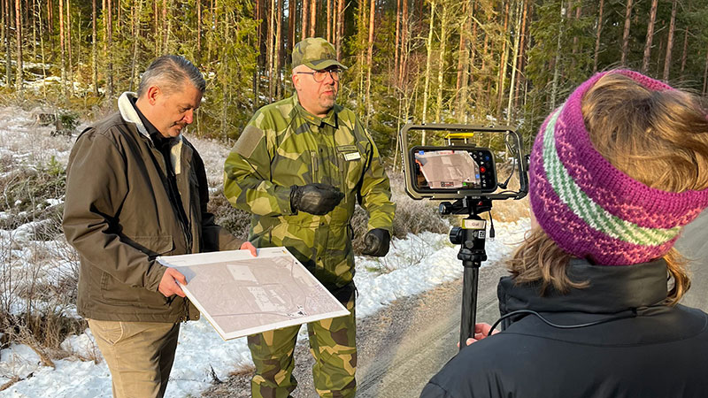 Två personer, en militär och en civilklädd, blir filmade av media