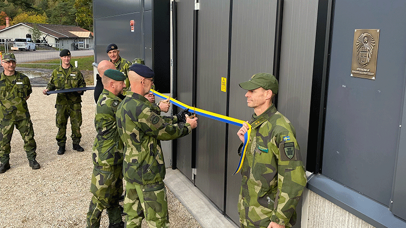 flera militärer klipper en gult och blått band.